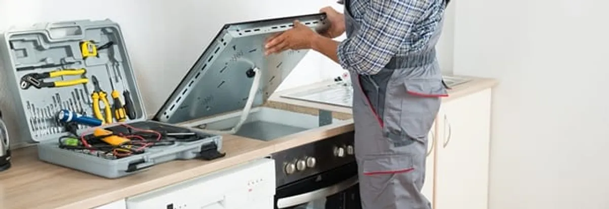 Cooktop repair technician lifting a built-in stovetop for service in Tempe, AZ