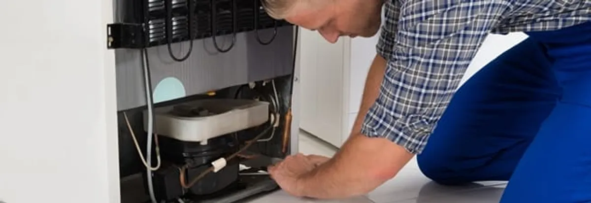 Refrigerator repair technician servicing the compressor and condenser area in Tempe, AZ